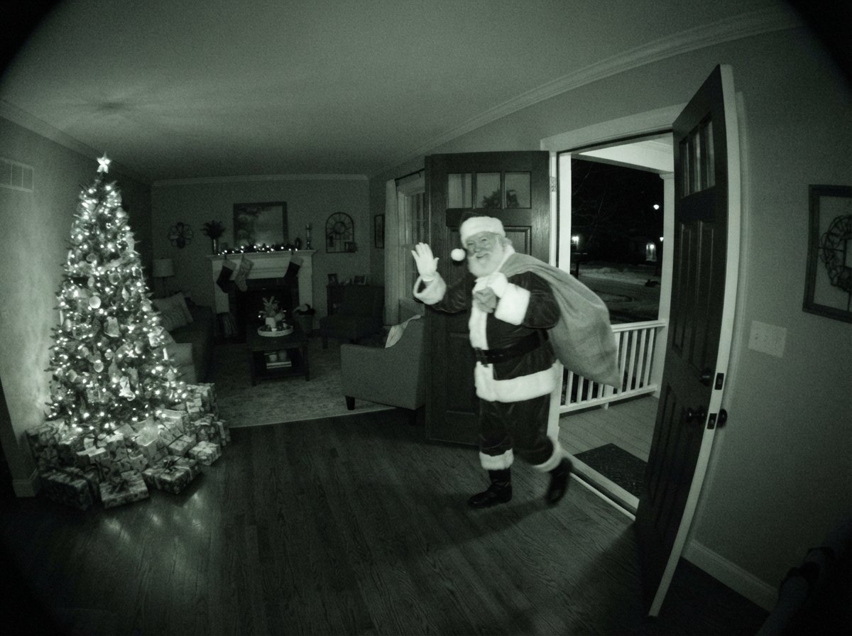 Santa caught on camera heading out through the hallway, second take — night-vision security camera still with CAM 01 label and timestamp